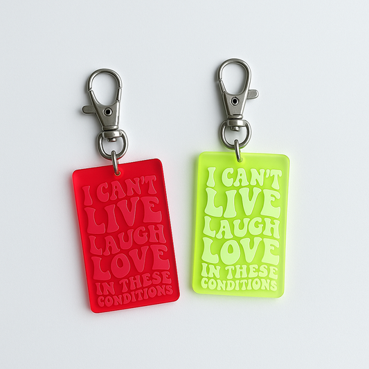 Retro motel-style keychain with engraved text reading ‘I Can’t Live Laugh Love in These Conditions,’ laser-cut acrylic accessory by Luna B Studios.