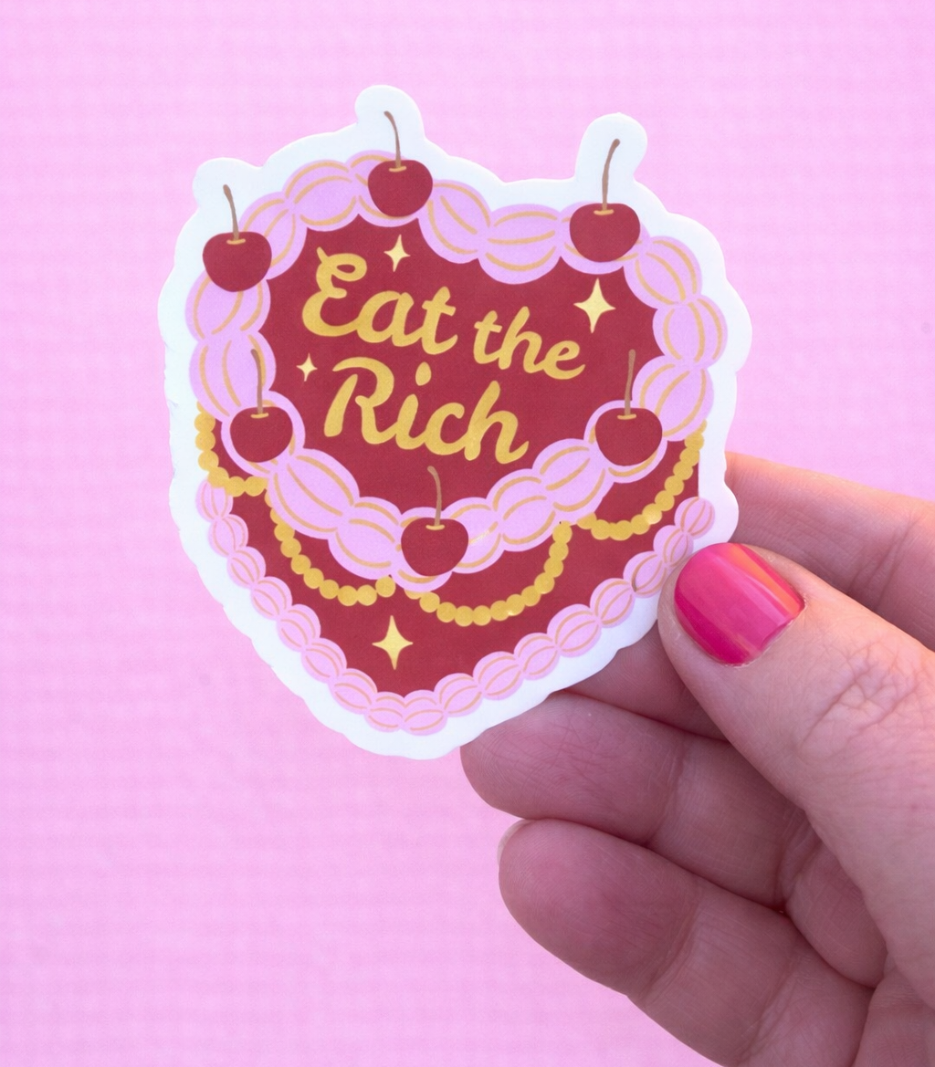Sticker with 'Eat the Rich' text held against a pink background