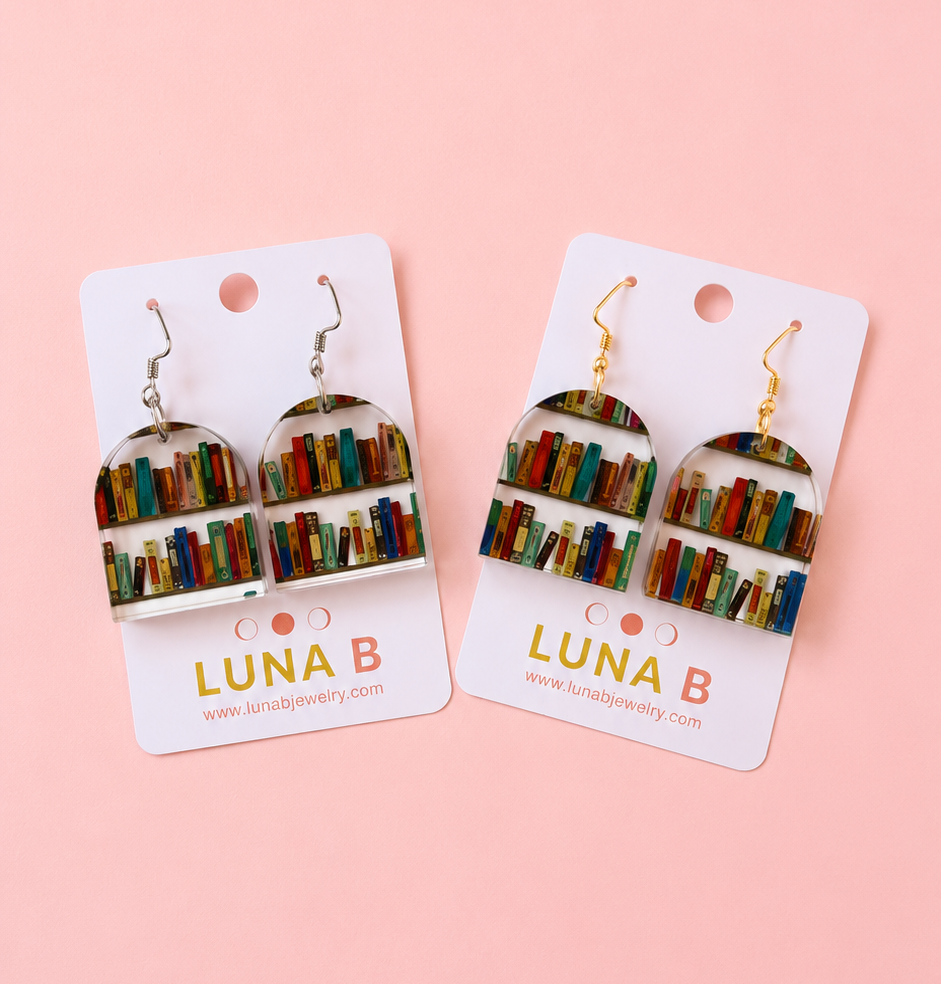 Two pairs of earrings on 'LUNA B' cards against a pink background