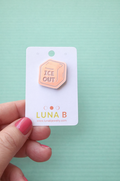 ICE OUT protest pin made from iridescent blue acrylic, engraved with “ICE OUT,” displayed on a Luna B Jewelry backing card against a pastel green background.