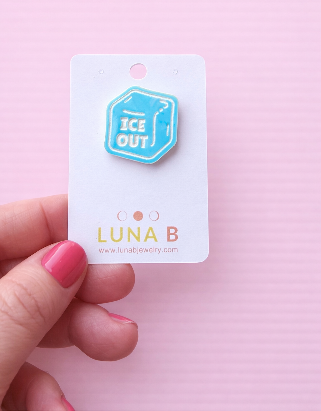 ICE OUT protest pin made from iridescent blue acrylic, engraved with “ICE OUT,” displayed on a Luna B Jewelry backing card against a pastel pink background.