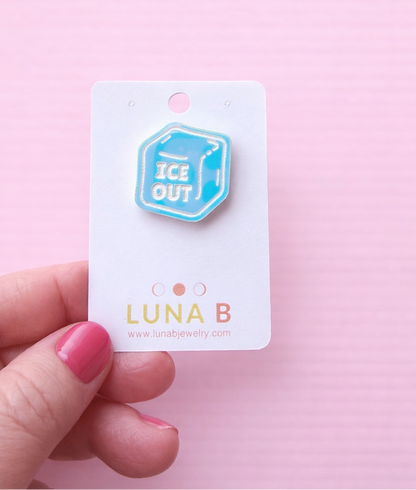 ICE OUT protest pin made from iridescent blue acrylic, engraved with “ICE OUT,” displayed on a Luna B Jewelry backing card against a pastel pink background.