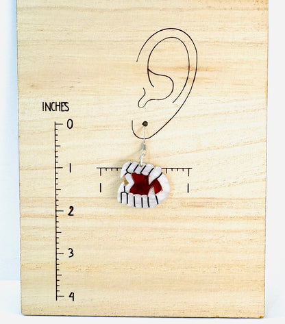 Earring on a wooden block with an ear illustration and measurement scale