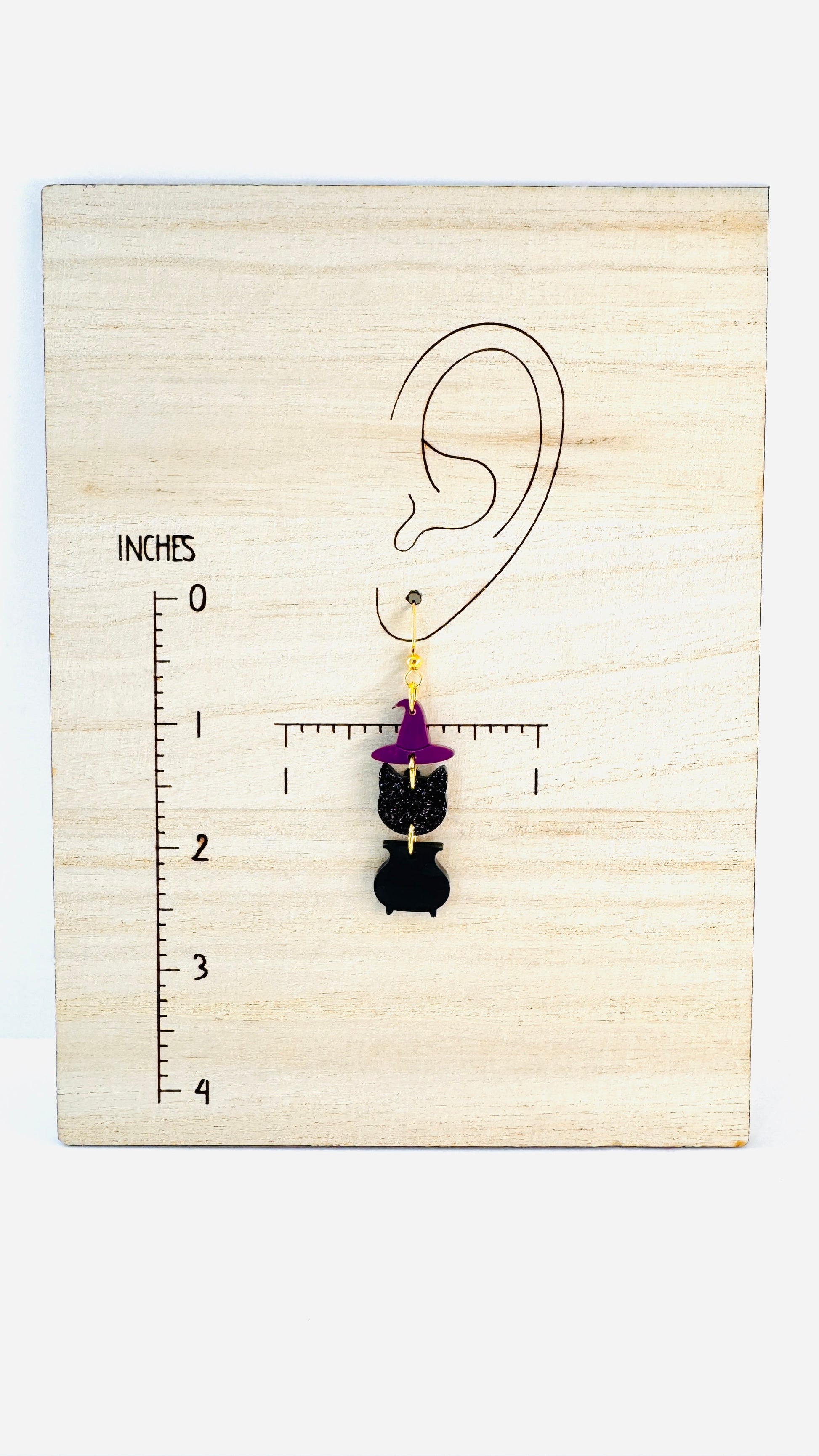 Earring displayed on a wooden block with an ear illustration and measurement scale.