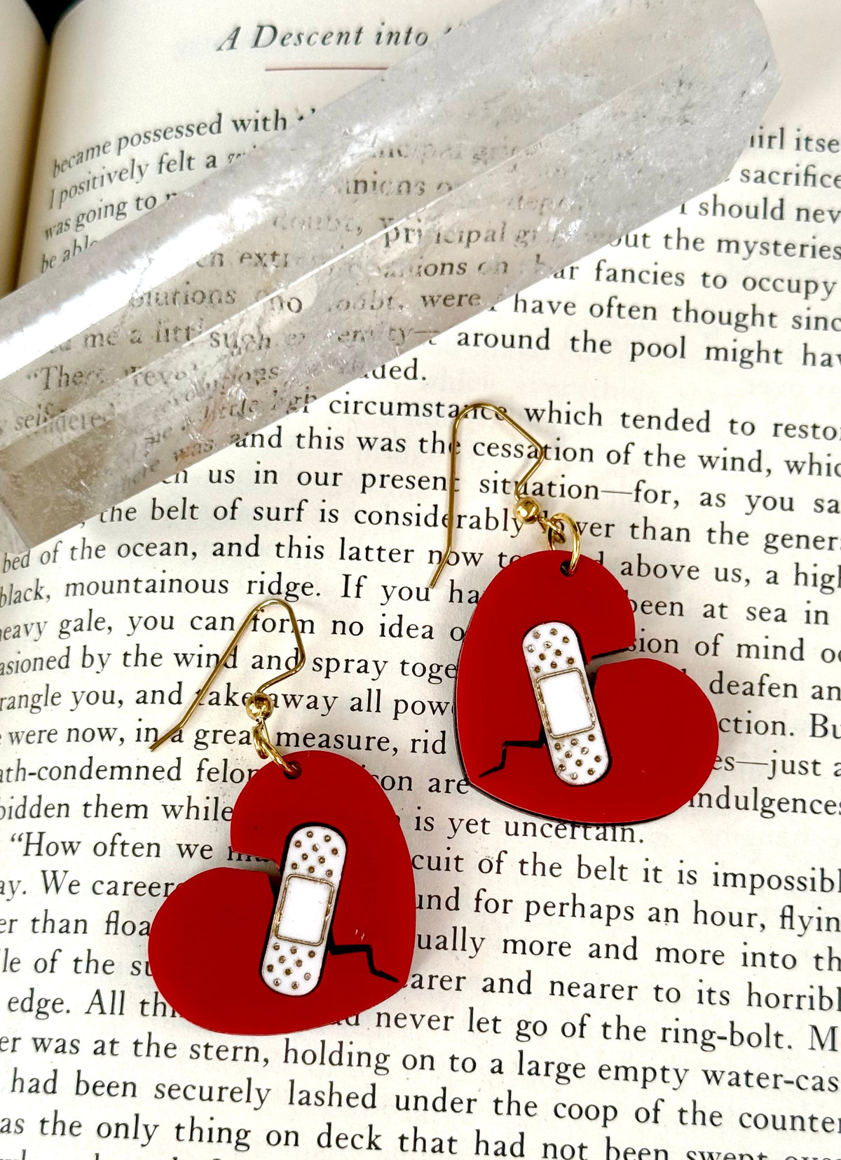 Two red and white patterned bandana-style headbands with gold details laid flat on a printed book page.