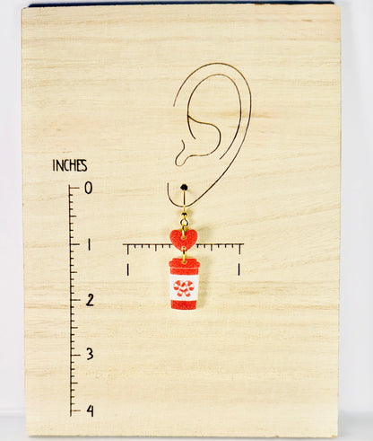 Earring with a cup and heart design on a wooden block with measurement scale