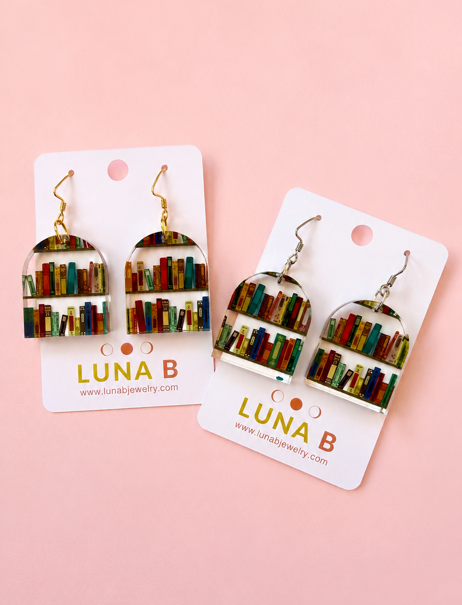 Pair of earrings on LUNA B branded cards against a pink background