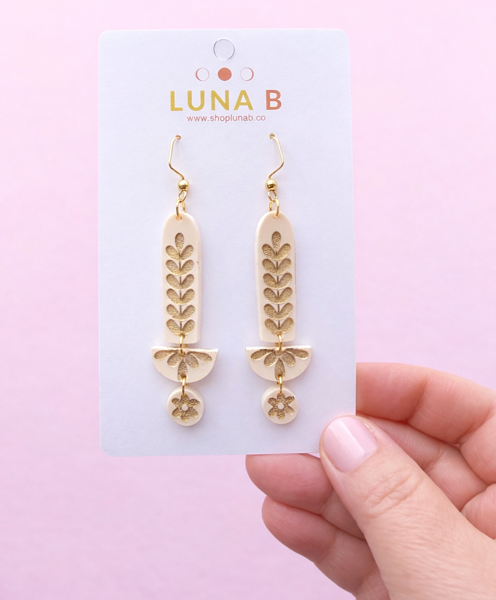 Gold leaf earrings on a Luna B card against a pink background