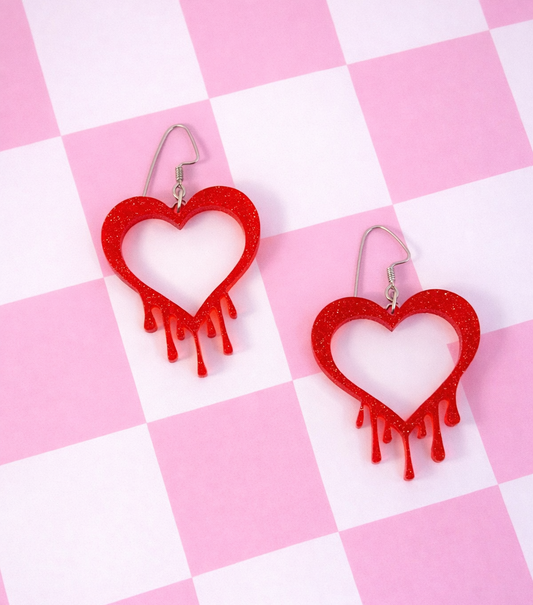 Red glitter drippy heart earrings on a soft pink background, featuring open heart shapes with dripping details and stainless steel ear wires