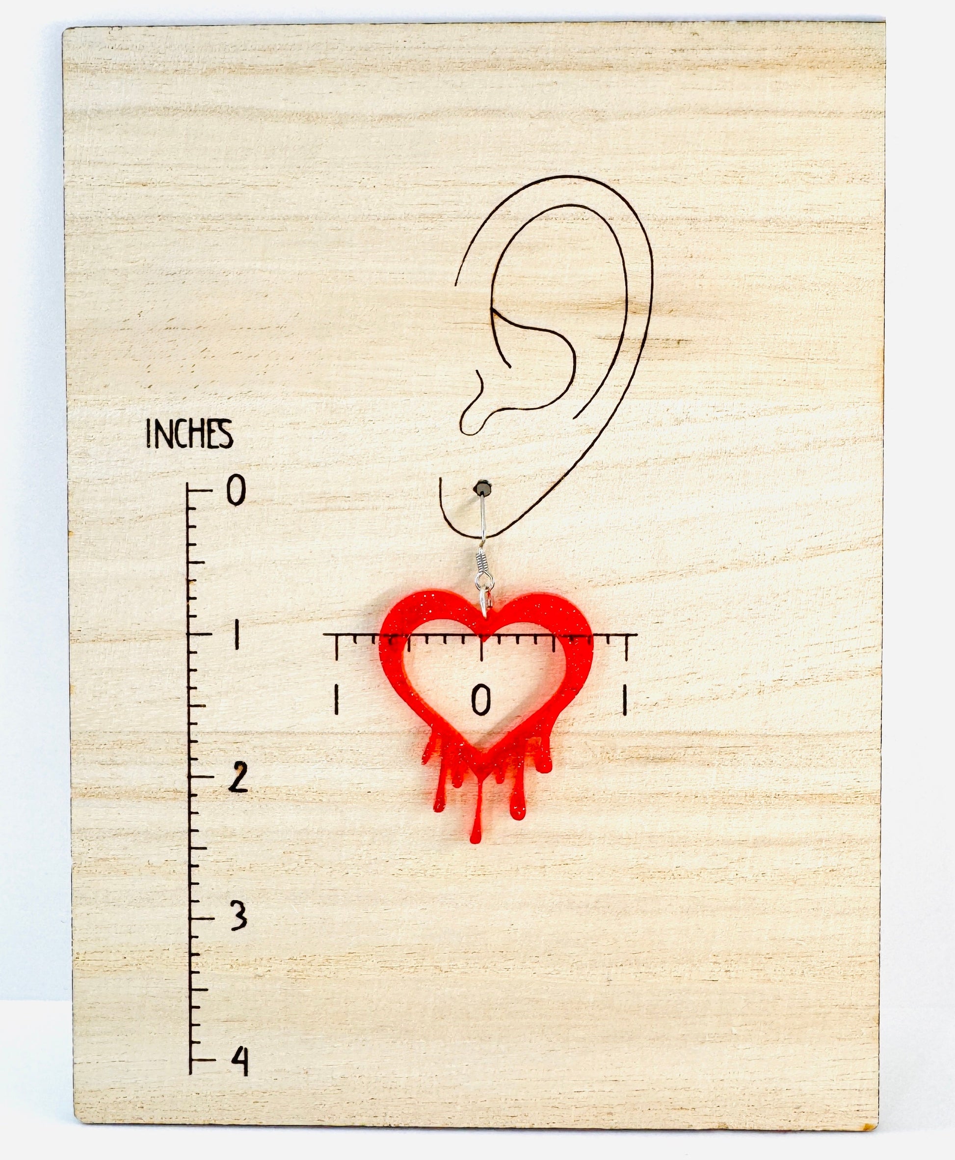 Wooden ear gauge with a heart-shaped hole and measurement scale on a light wood background