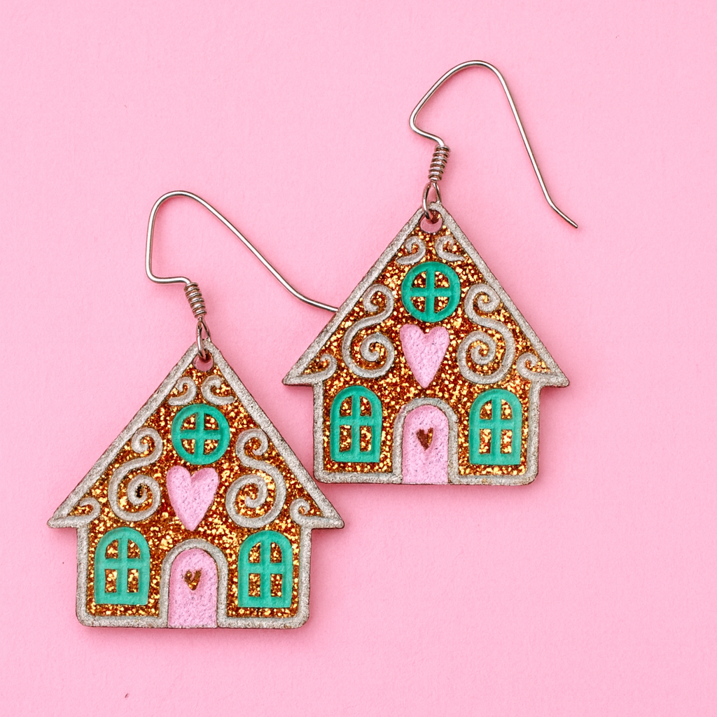 Gingerbread house earrings on a pink background