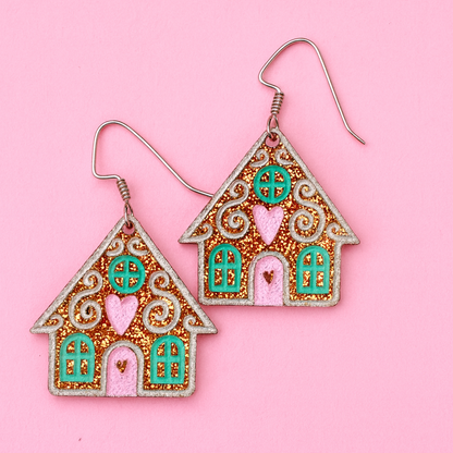 Gingerbread house earrings on a pink background