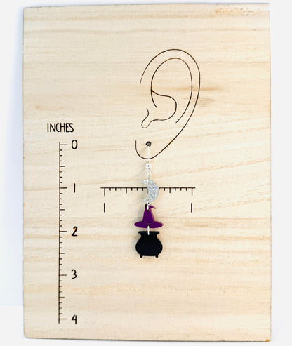 Earring displayed on a wooden block with an ear illustration and measurement scale.