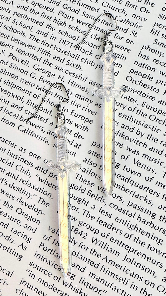 Vintage inspired sword earrings on a background of text from a book